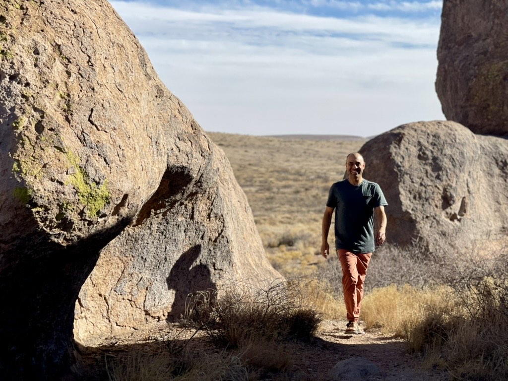 Ben hiking between large boulders in high desert